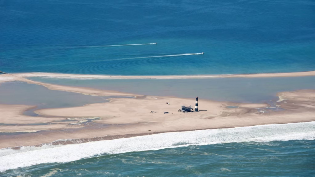 An aerial photograph of the Pelican Point Lighthouse, sweeping sand banks and ocean.